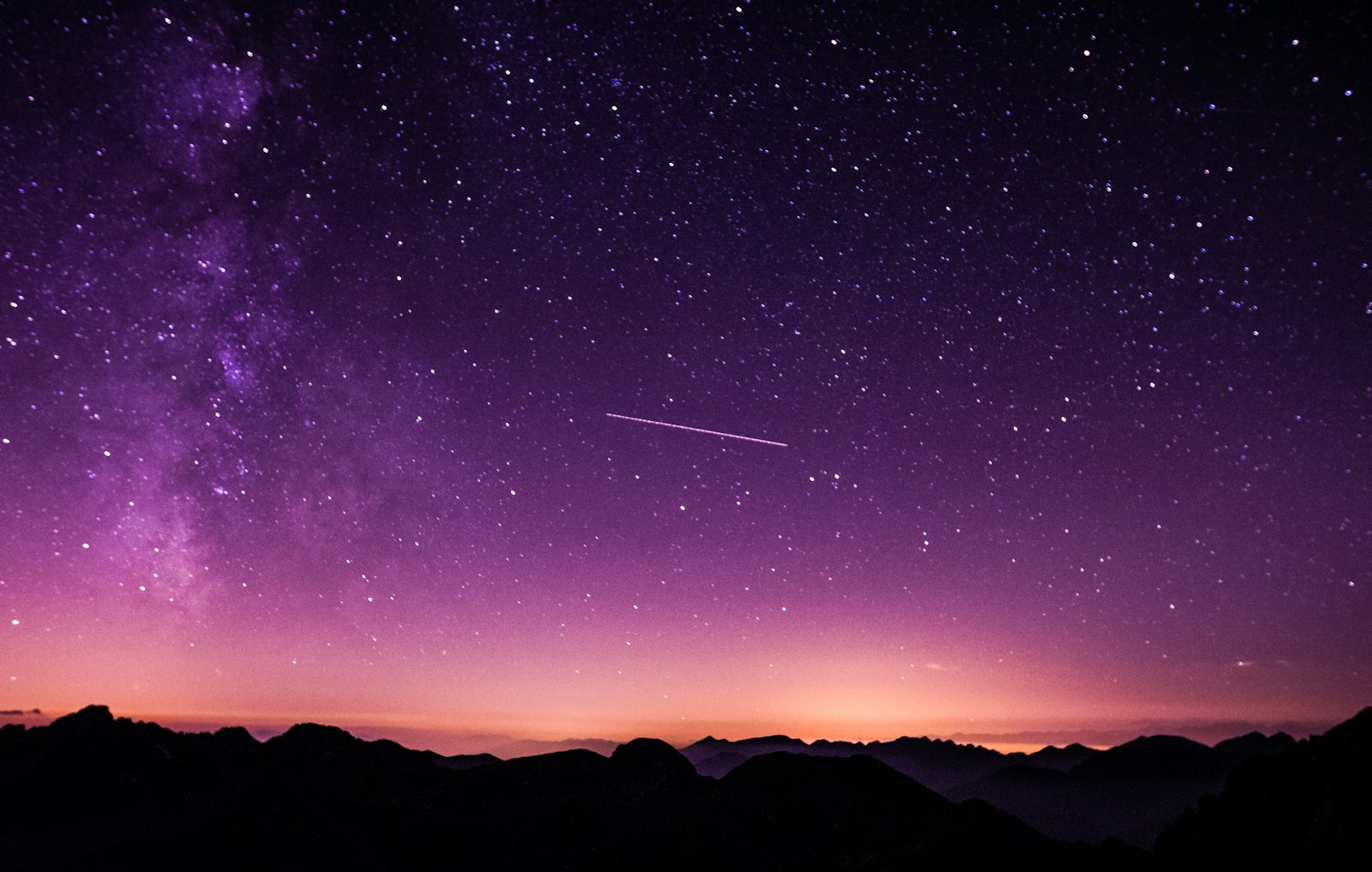 Cielo estrellado en tonos violeta sobre siluetas de montañas