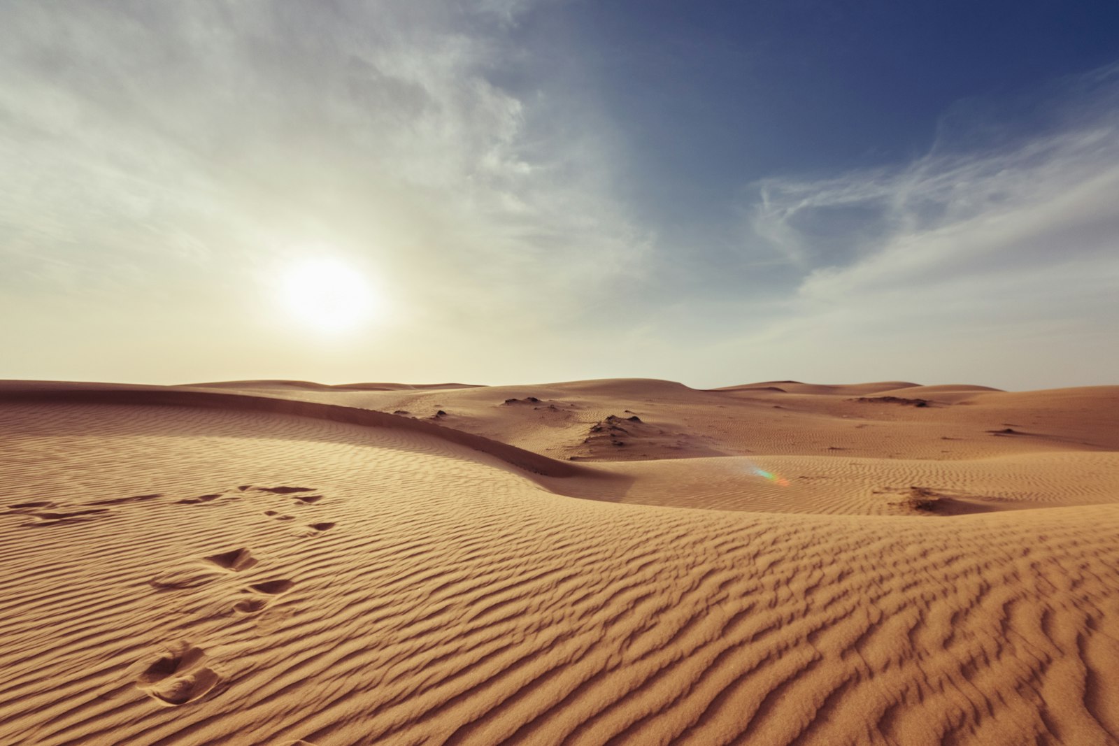 Dunas doradas al atardecer con huellas en la arena
