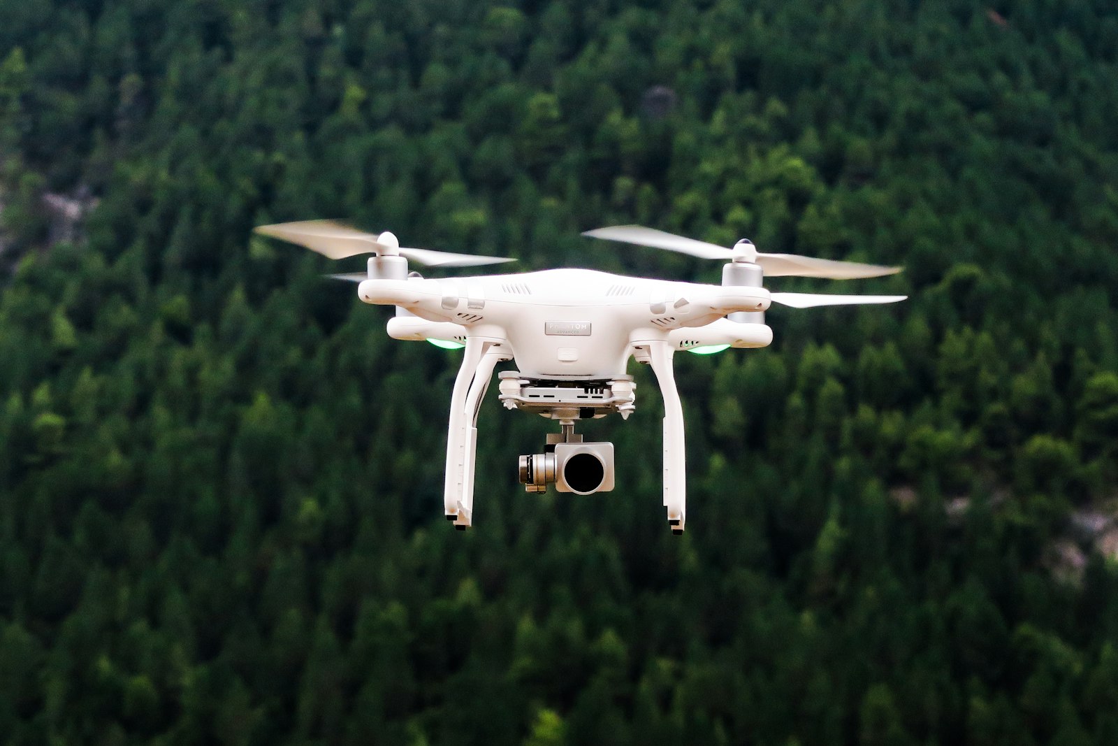 Dron blanco sobrevolando una zona arbolada