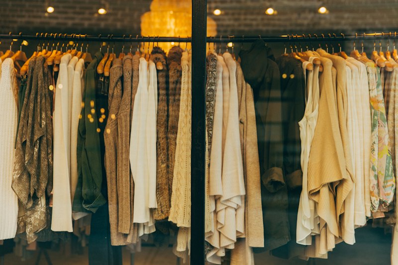 Abrigos y tejidos en tonos crudos en el aparador de la boutique