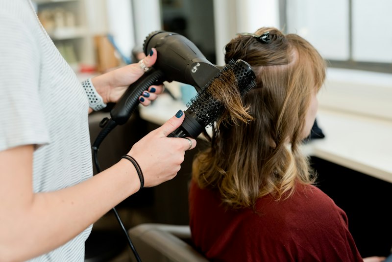Estilista cepillando y secando el cabello de una clienta