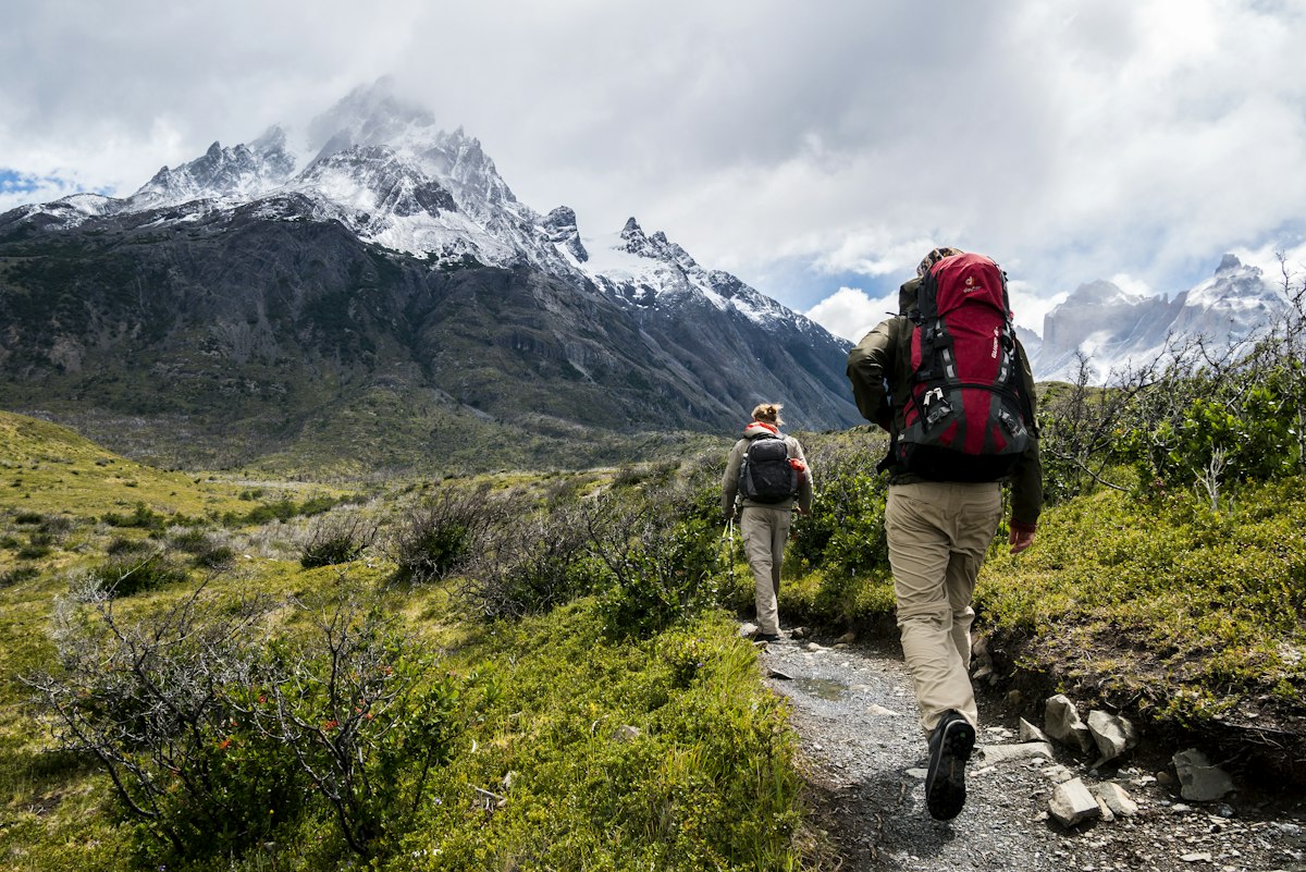 Viajeros con mochila caminando hacia montañas nevadas